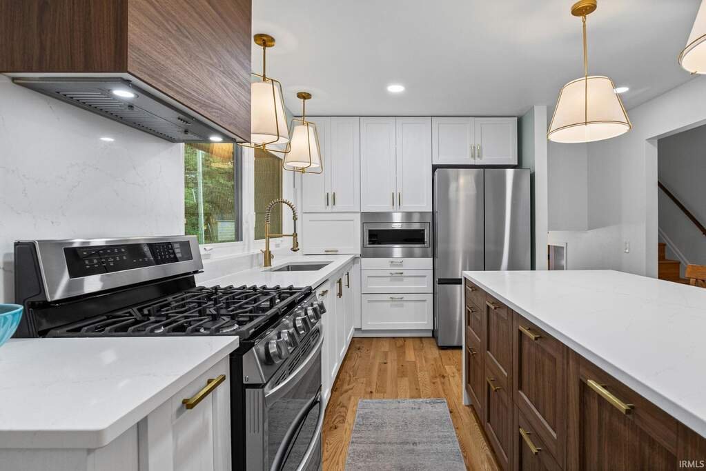 Renovated kitchen with white cabinets, quartz counters and a gas range