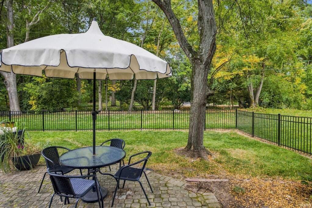 Paver patio under mature trees with a table and umbrella